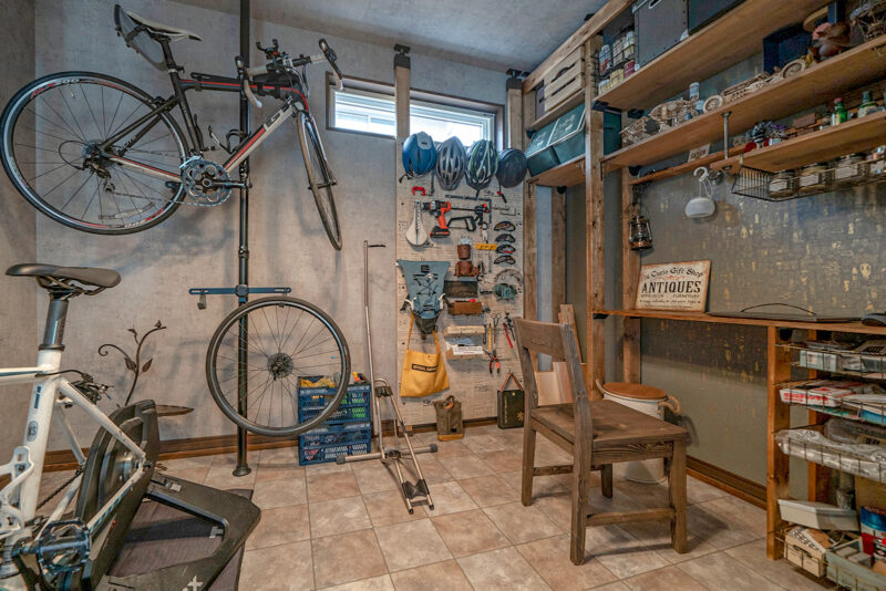 夫妻念願の趣味部屋。 ご主人の DIY 工具やロードバイク関連のアイテムが整然と並ぶ。ロードバイクは掃き出し窓から、そのまま外へ持ち出せる設計。<br />
