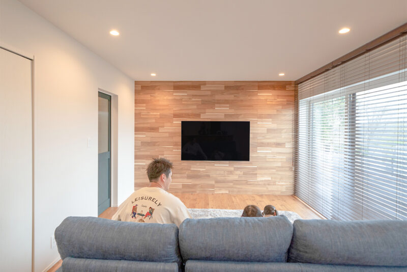 テレビ背面の壁には木目の美しいアカシアを採用。デザイン性と掃除のしやすさを考慮し、徹底的に物を置かない LDK を実現した。<br />
