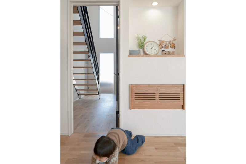 玄関ドアを開けると現れるのは、インパクト大のスケルトン階段。 子どもが大きくなった時に、リビングを通らずに自分の部屋に行ける様に、という理由もある。 写真右手の木の格子部分の裏には、テレビ関係の機器がスマートに収納されている。雑多になってしまう配線を隠すアイデア。<br />
