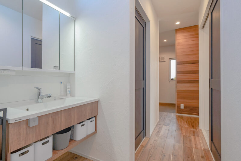 洗面室には玄関から直接アクセスできる。 行き止まりのない回遊できる動線設計だ。漆喰の調湿効果で室内干しでもあっという間に乾くそう。<br />
