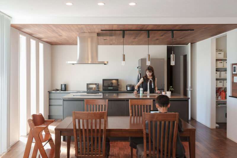 キッチン上部の下がり天井にも、意匠としてウォールナットをあしらった。主役は奥さまご希望のアイランドキッチン。「ダイニング側に収納があるので、いつもキッチンはスッキリとした状態に保っておけるんです」と奥さま。天板には上質な風合いでキズが付きにくいクォーツストーンをセレクト