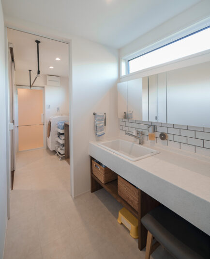 洗面室は広めに設計。流しは最近人気となっている病院用シンクをセレクトした。「深さがあるので汚れがひどい靴下などをまとめて洗うのに便利！」と奥さま。奥に見える脱衣所はランドリースペースも兼ねている。室内干しがT 家の基本スタイル。