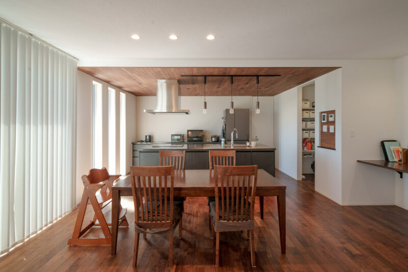 キッチン上部の下がり天井にも、意匠としてウォールナットをあしらった。主役は奥さまご希望のアイランドキッチン。「ダイニング側に収納があるので、いつもキッチンはスッキリとした状態に保っておけるんです」と奥さま。天板には上質な風合いでキズが付きにくいクォーツストーンをセレクト