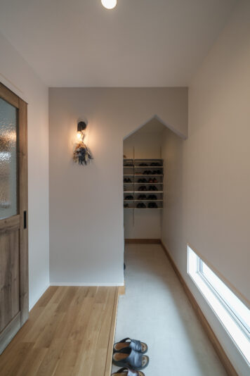 玄関収納は、収納力を優先して扉を付けずにL字型に棚を配置。