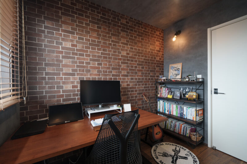 書斎は寝室とつながっているので、寝室のエアコンを回して快適に過ごせる。ご主人はテレワークなので、座っても立っても仕事できるように昇降式のデスクを採用。「長時間座って疲れた時は、立って仕事するとはかどるんです」とご主人。この部屋はご主人の「好き」が詰まったブルックリンスタイル。<br />
