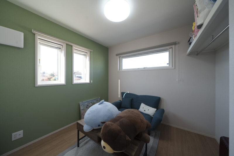 落ち着いたグリーンの壁が印象的な子ども部屋。収納は広く使えるように扉を付けない設計に。